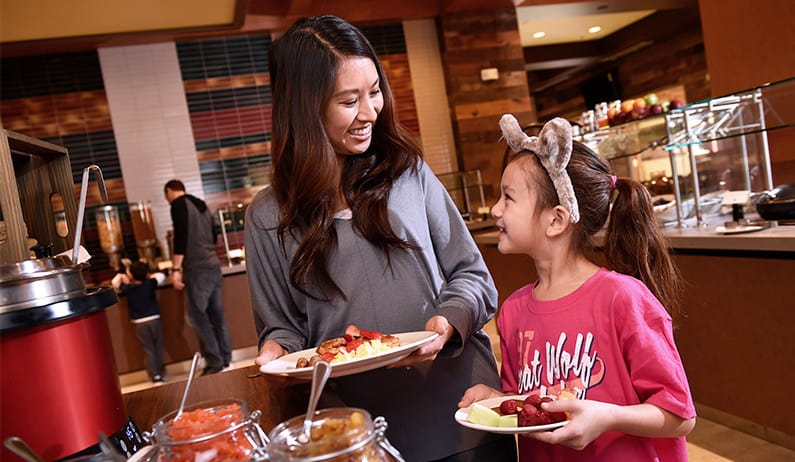 Mom and daughter grabbing food from buffet
