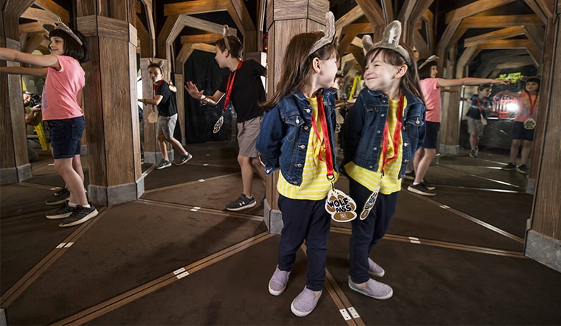 Little girl smiles at her reflection inside the mirror maze of Oliver's mining.